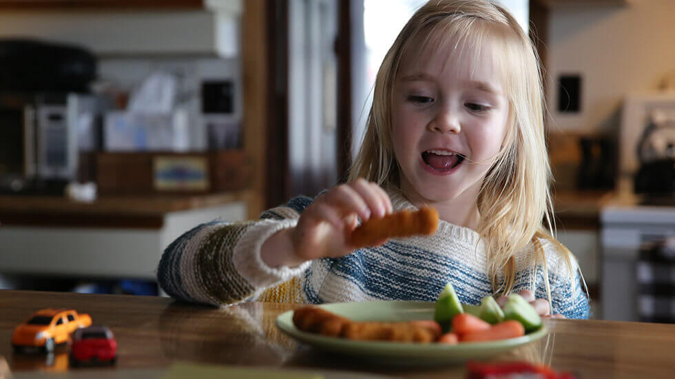 Little girl excited to eat nuggets and veggies