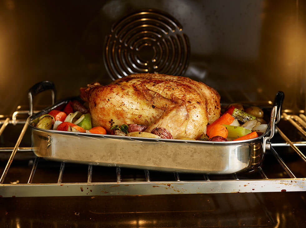 Whole chicken with veggies on a roasting pan